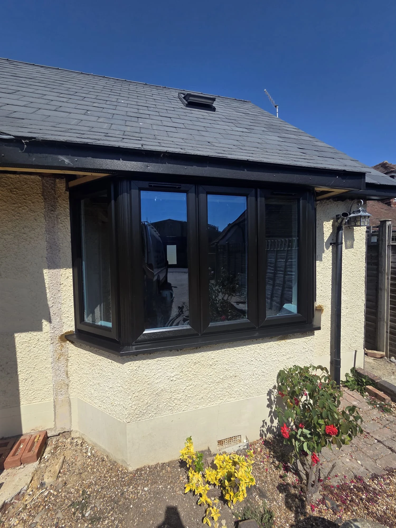 Black bay window with matching black cill against the cream render