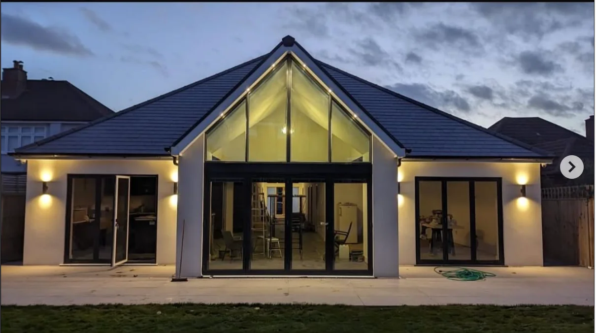 Gable house at dusk — full-elevation architectural glazing, Surrey, by A1 Window Construction Ltd